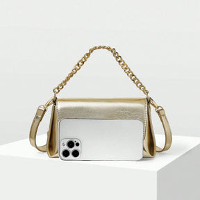 Bolsa pequena Melissa Mayzê dourada. Design tiracolo em couro ecológico, alça de corrente e fechamento magnético. O brilho ideal para festas e eventos especiais.